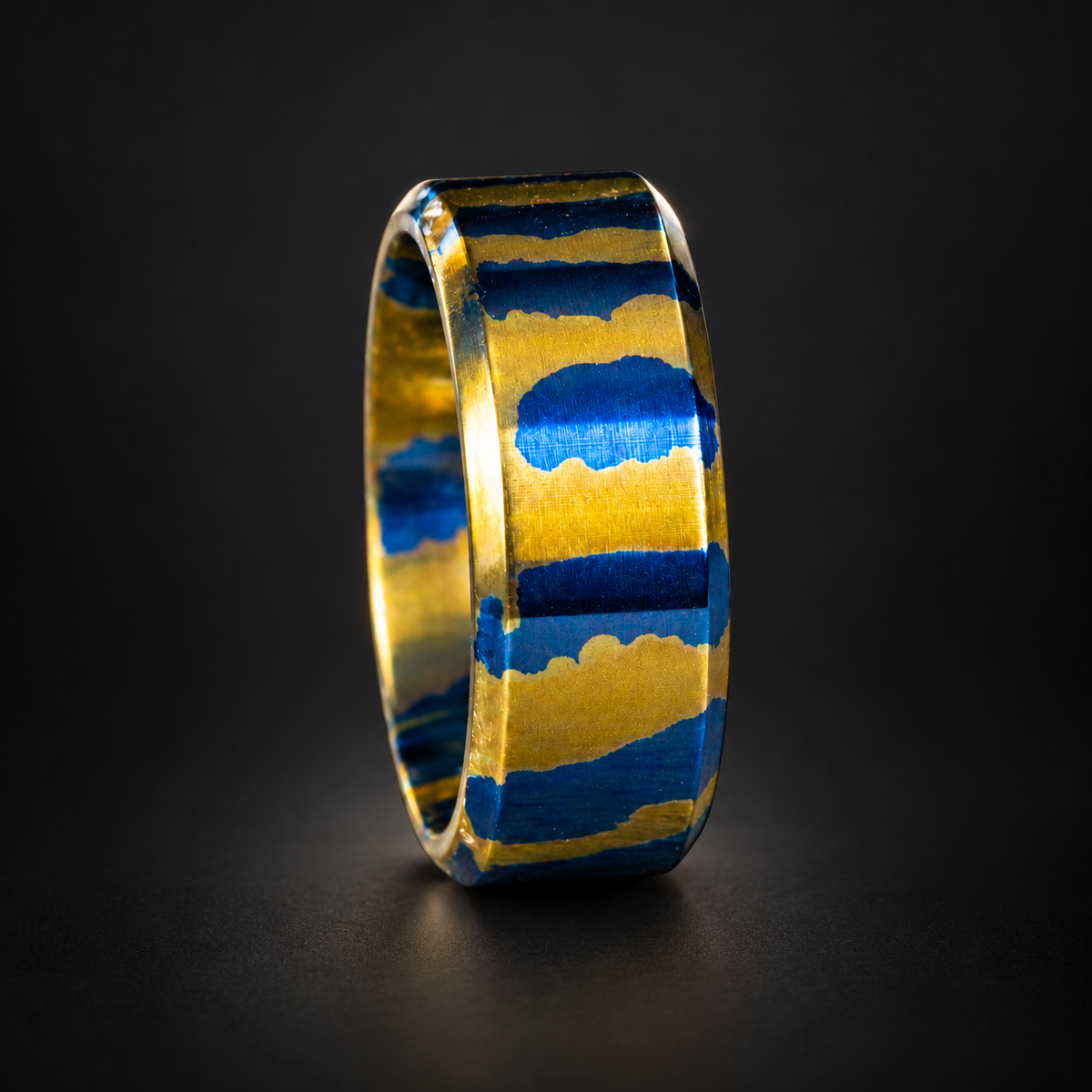 The Animal gold and blue anodized titanium band on a dark studio background