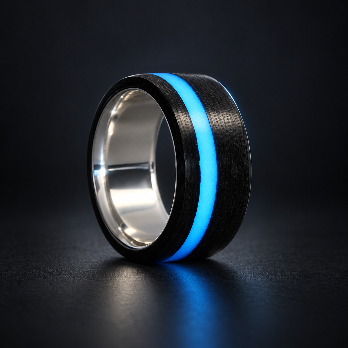 Sterling silver and carbon fiber ring with an offset blue lume stripe on a dark studio background